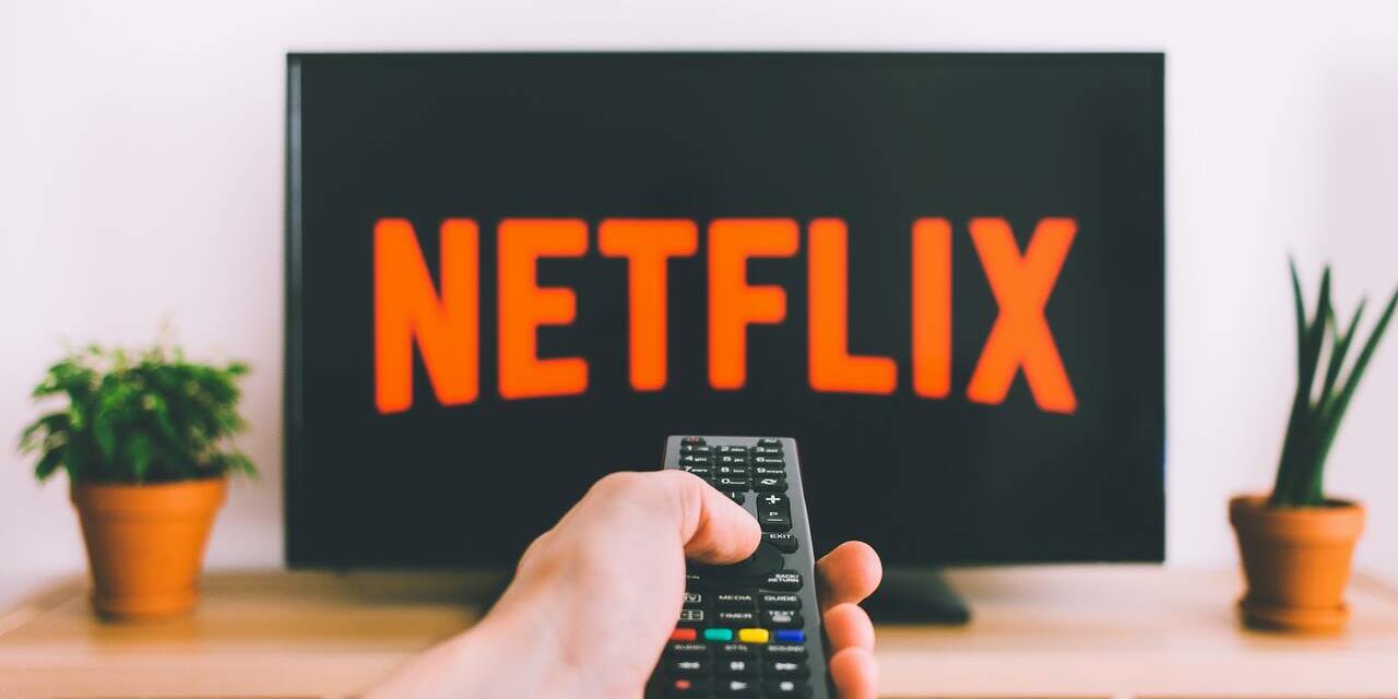 TV mit Netflix-Logo und Hand mit Fernbedienung